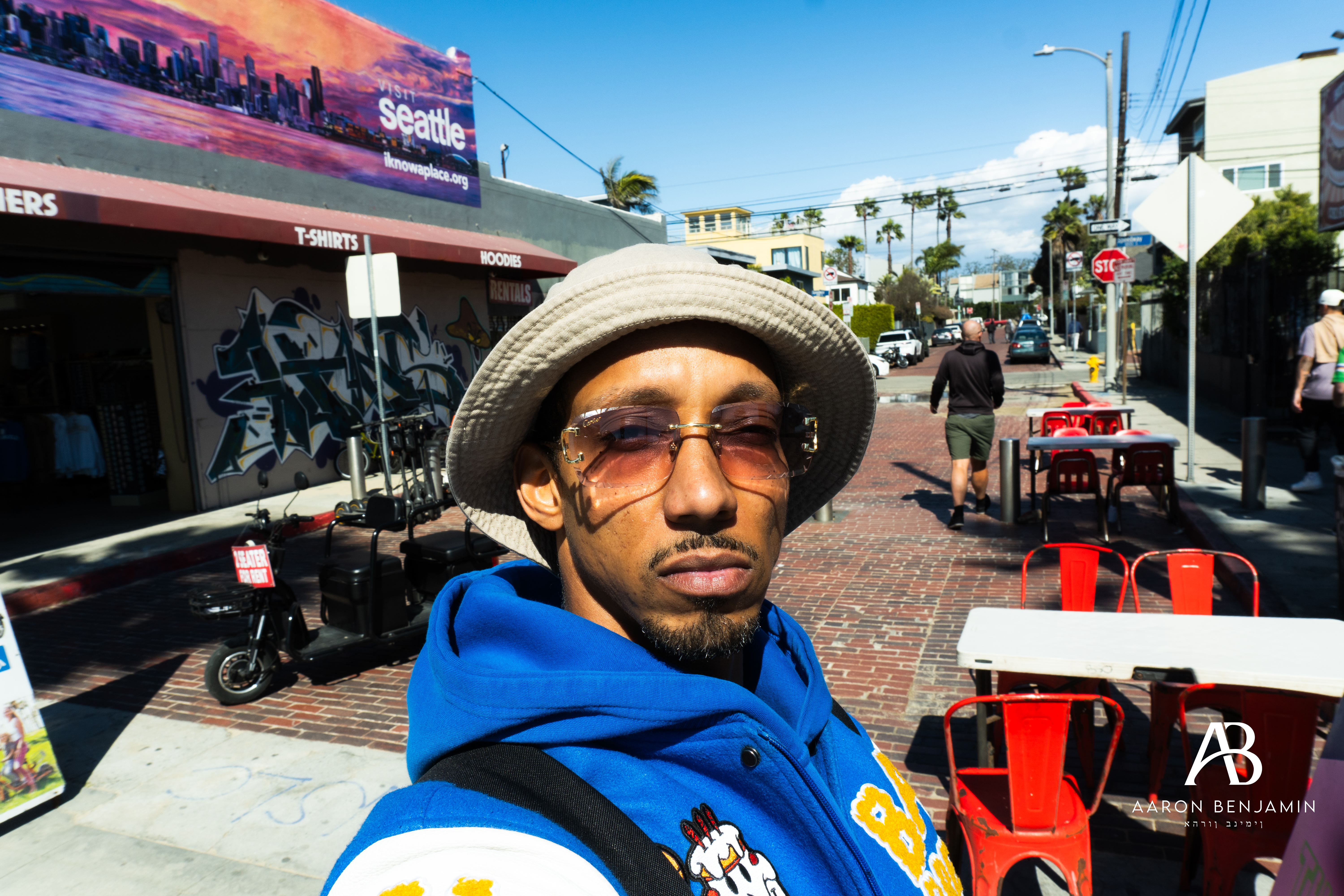 Aaron Benjamin at Venice Beach wearing a bucket hat with a blue jacket on